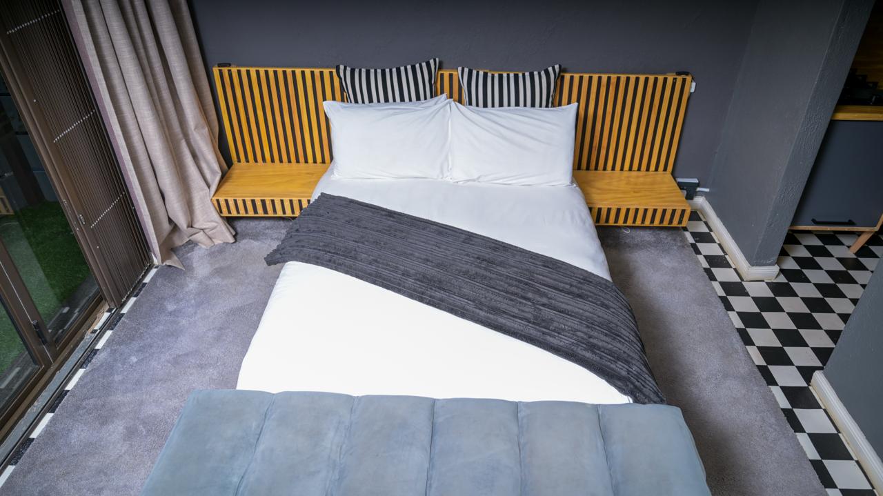 The Dark Room — queen bed with blackout curtains and checkered floor