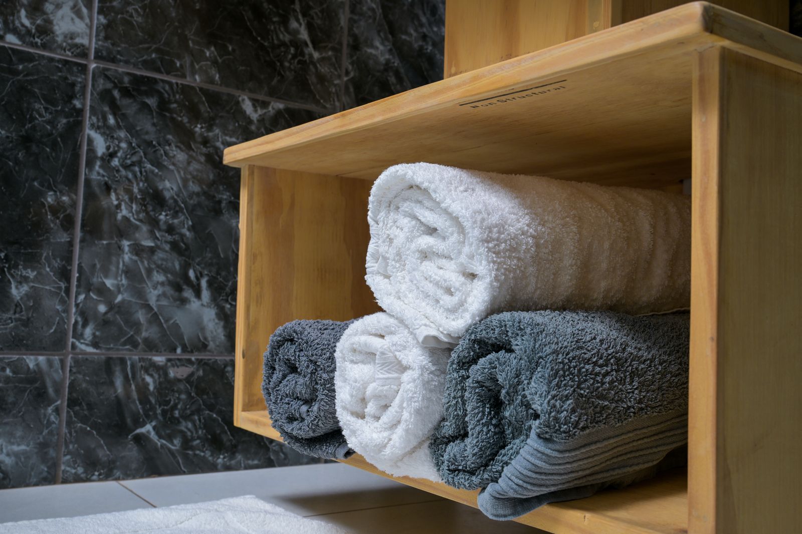 The Dark Room — fresh white and grey towels on a timber shelf