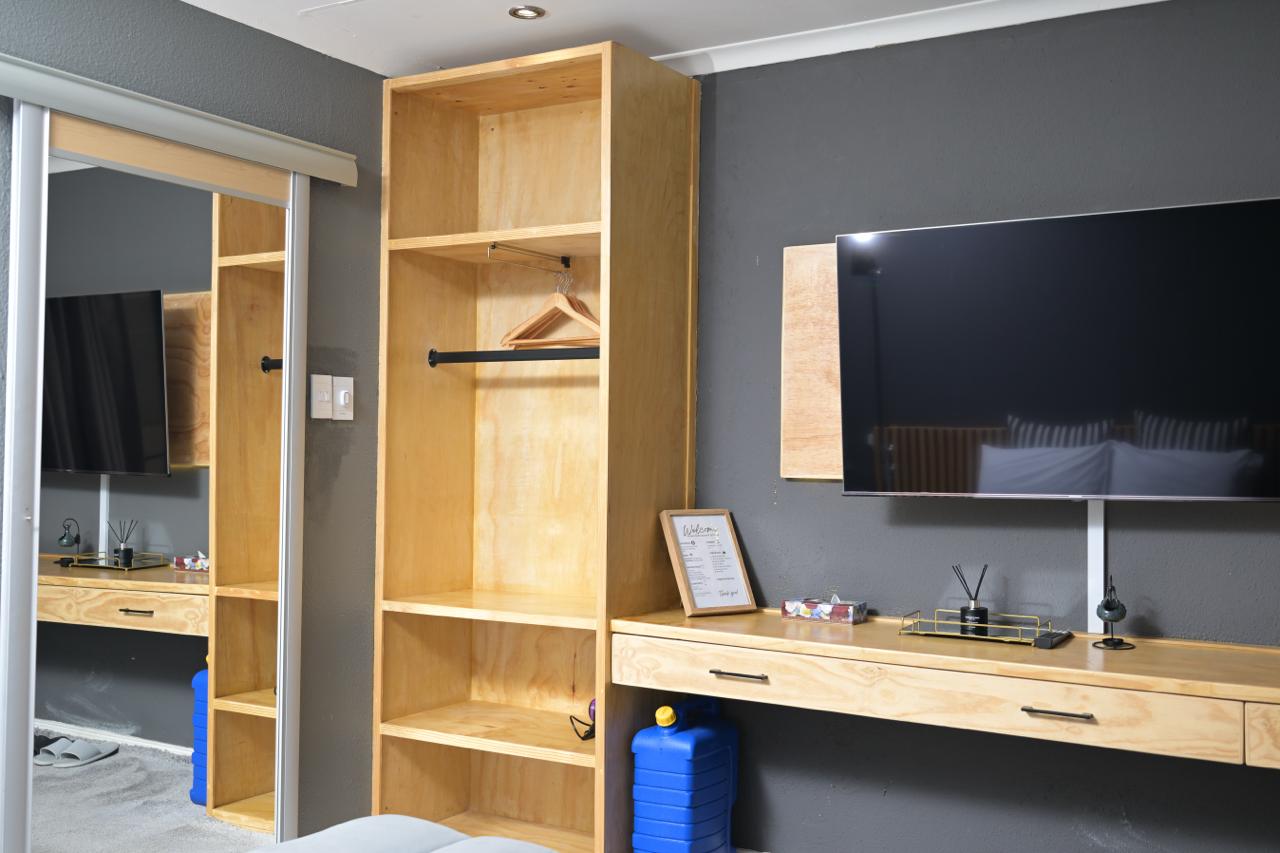 The Dark Room — open wardrobe, dresser and wall-mounted TV