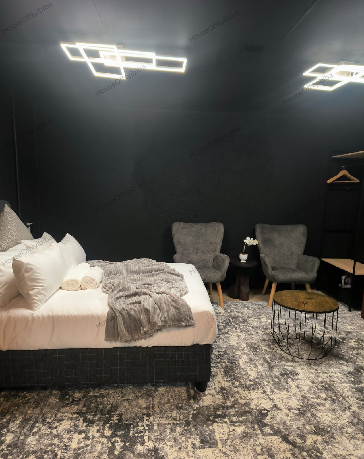 Zululami — queen bed and lounge chairs under geometric ceiling lights