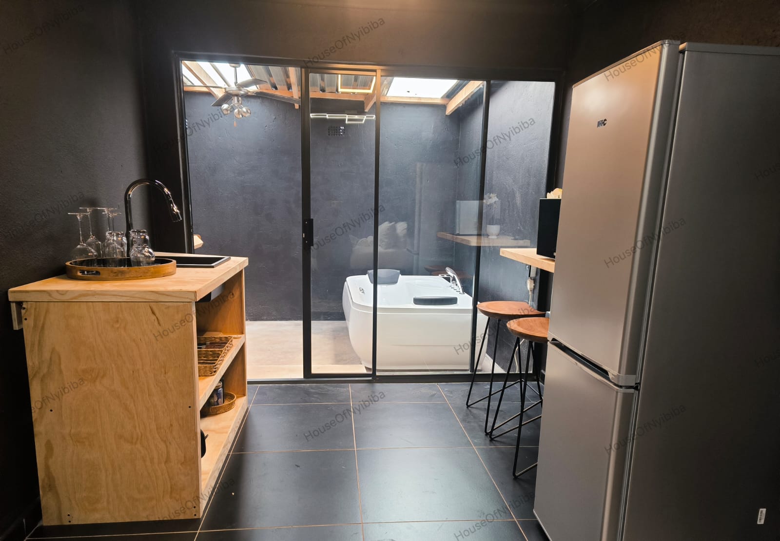 Zululami — kitchenette with fridge and the hot tub beyond the glass doors